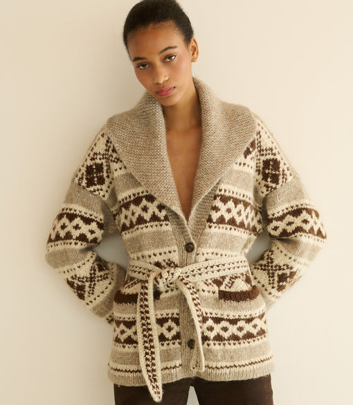 Woman wearing a patterned cardigan against a plain background
