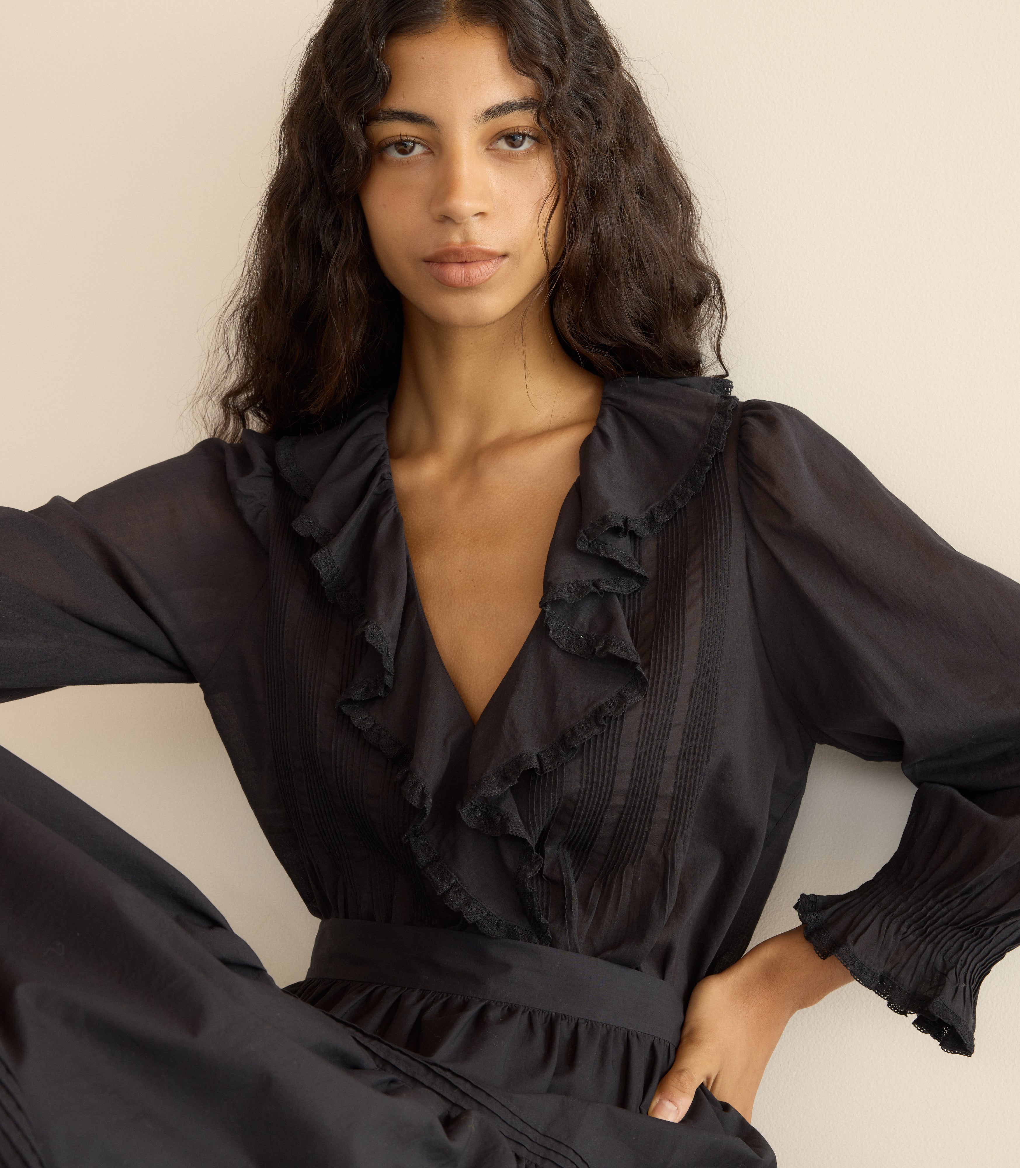 Woman wearing a black ruffled blouse against a neutral background