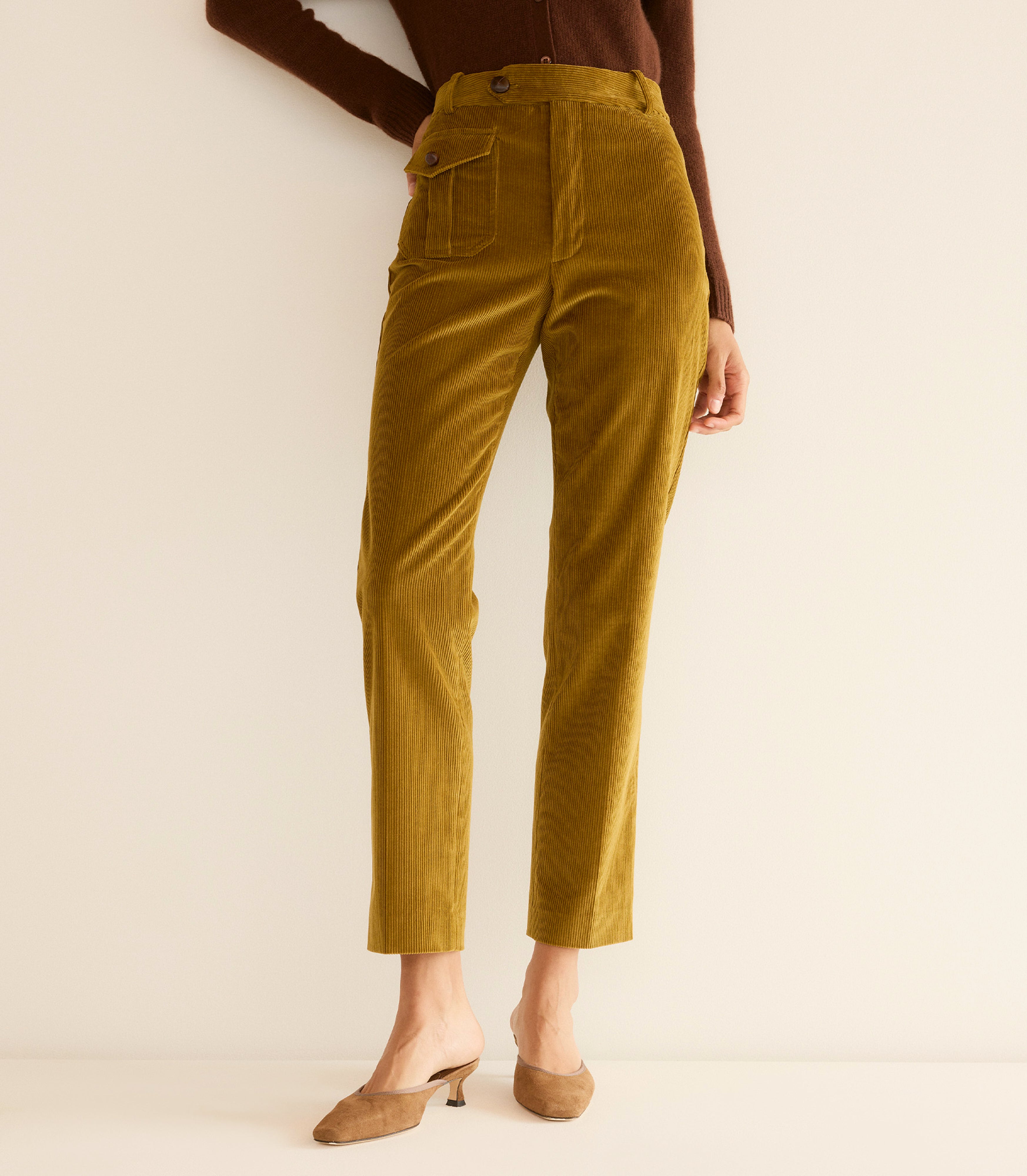 Mustard yellow pants worn by a person on a beige background