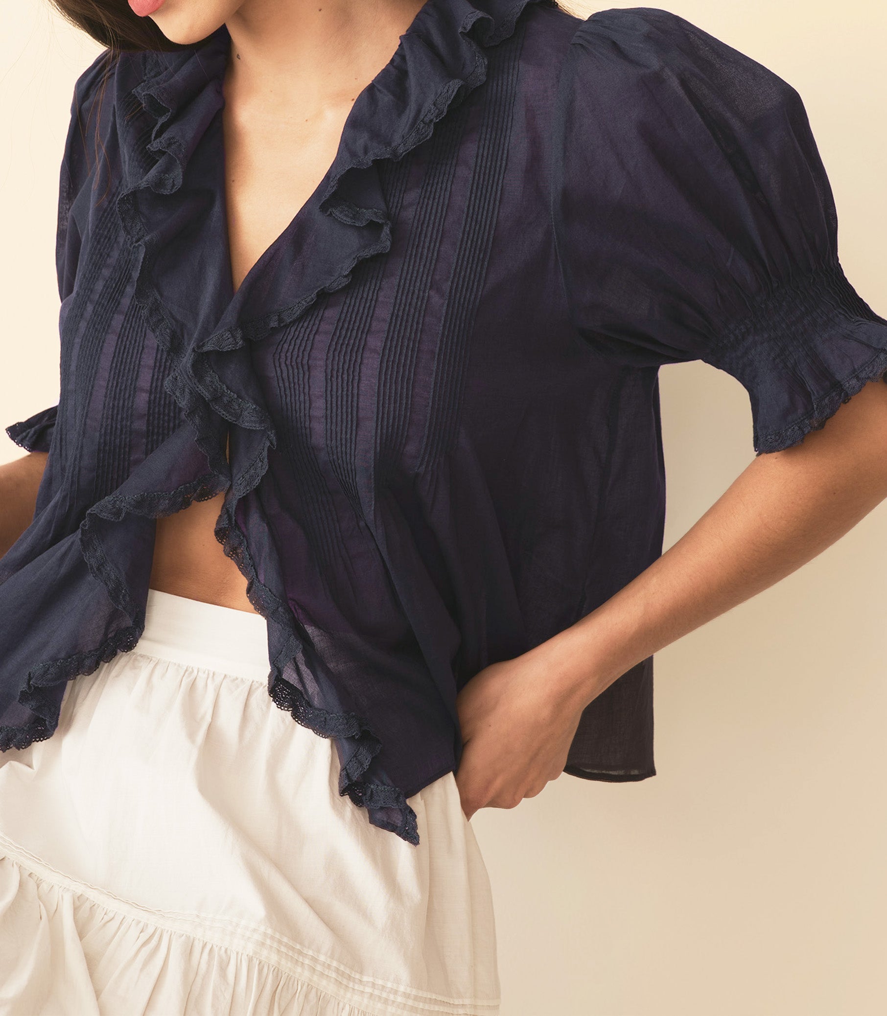Navy blue ruffled blouse worn by a person on a beige background 1