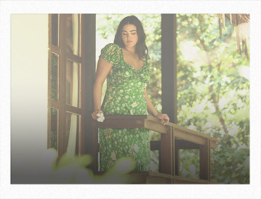 Woman in floral green dress standing in a balcony