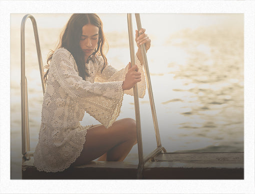 Woman sitting on a dock by a body of water, holding onto the railing.