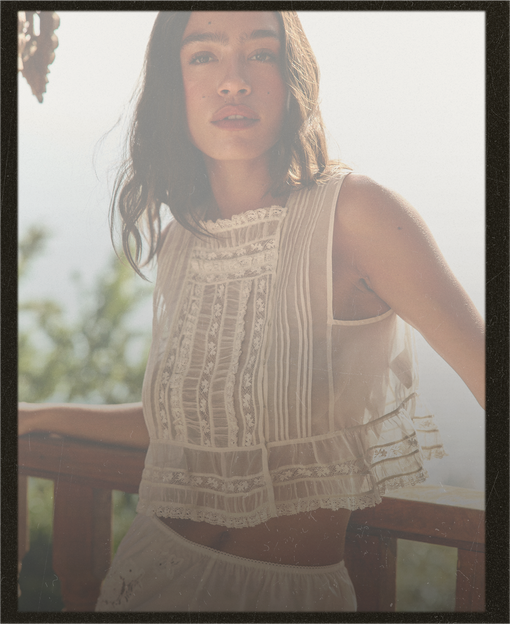 Woman wearing a white lace top and skirt outdoors with a blurred background