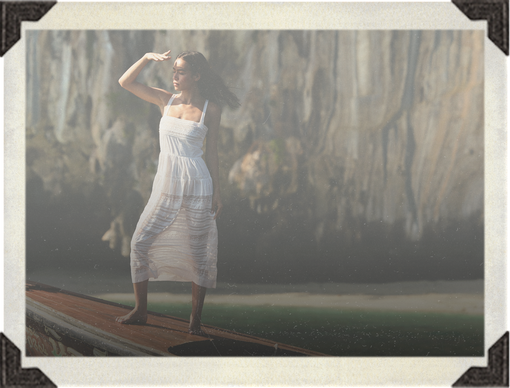 Woman in a white dress standing on a wooden boat with a natural background