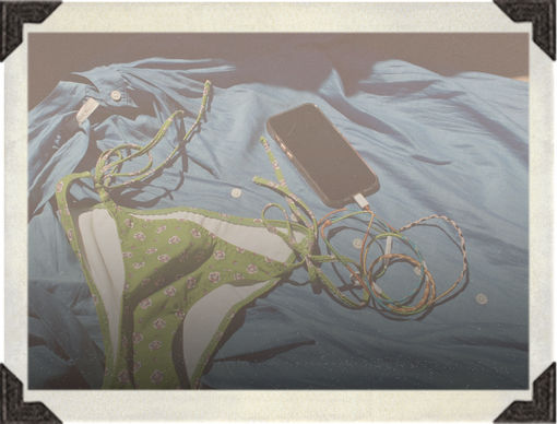 Green bikini bottom with a phone and earbuds on a blue fabric background