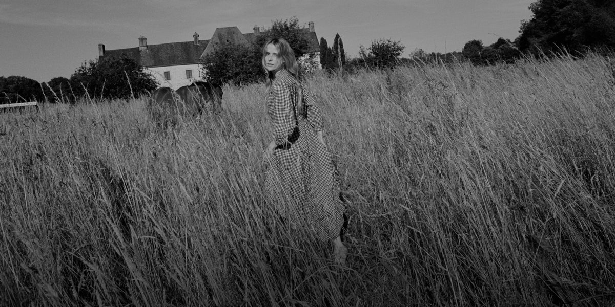 Woman in a checkered long sleeve maxi dress out in a field.