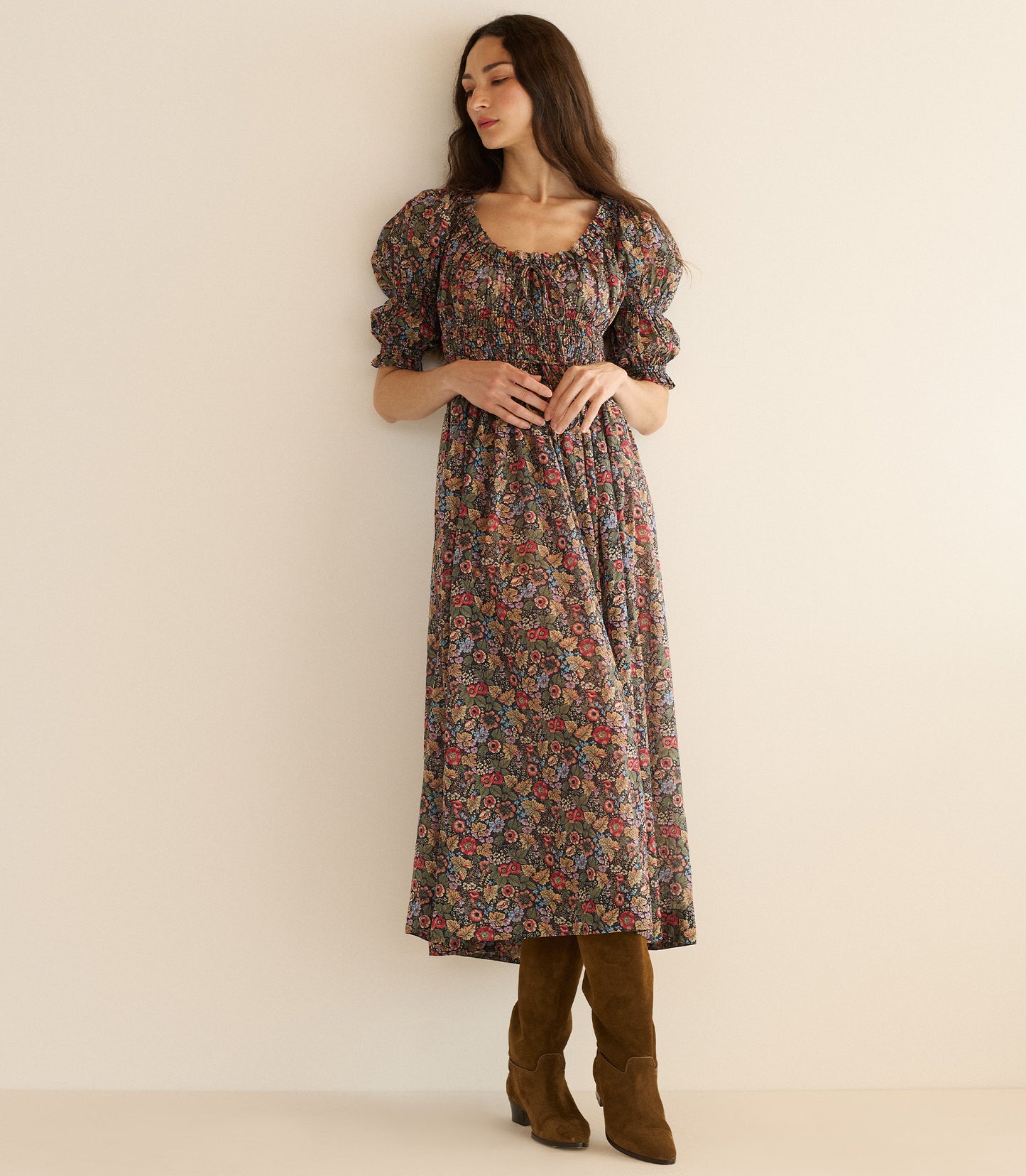 Woman wearing a floral dress with puffed sleeves against a plain background