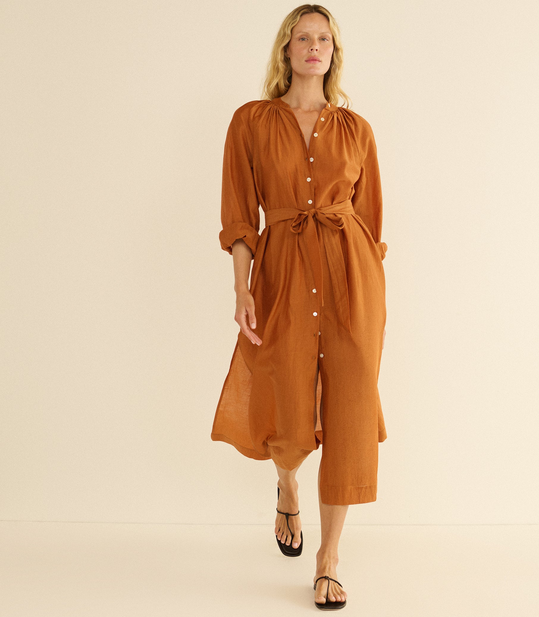 Woman wearing a brown dress against a beige background