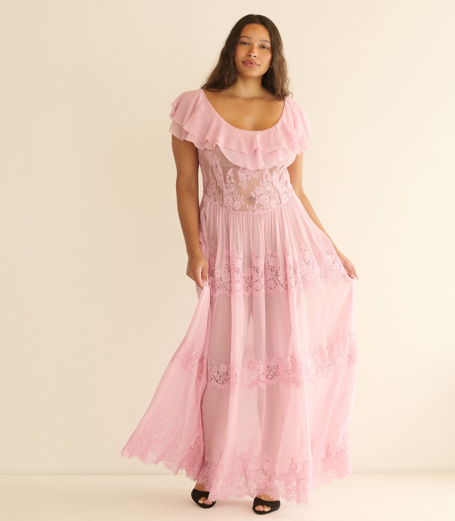 Woman wearing a pink dress with lace details on a beige background