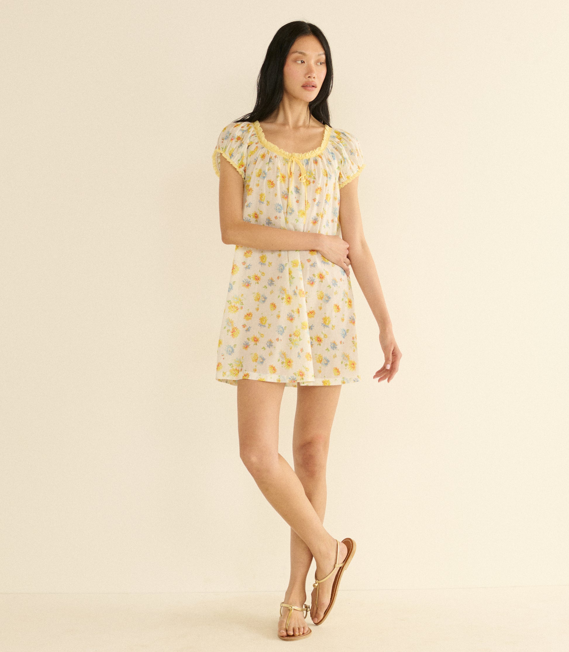 Woman wearing a white floral dress on a beige background 1
