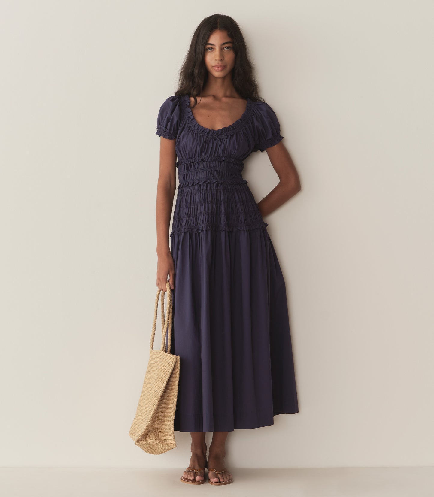 Rocio wears a dark blue dress with puffed sleeve and ruching along the bodice.