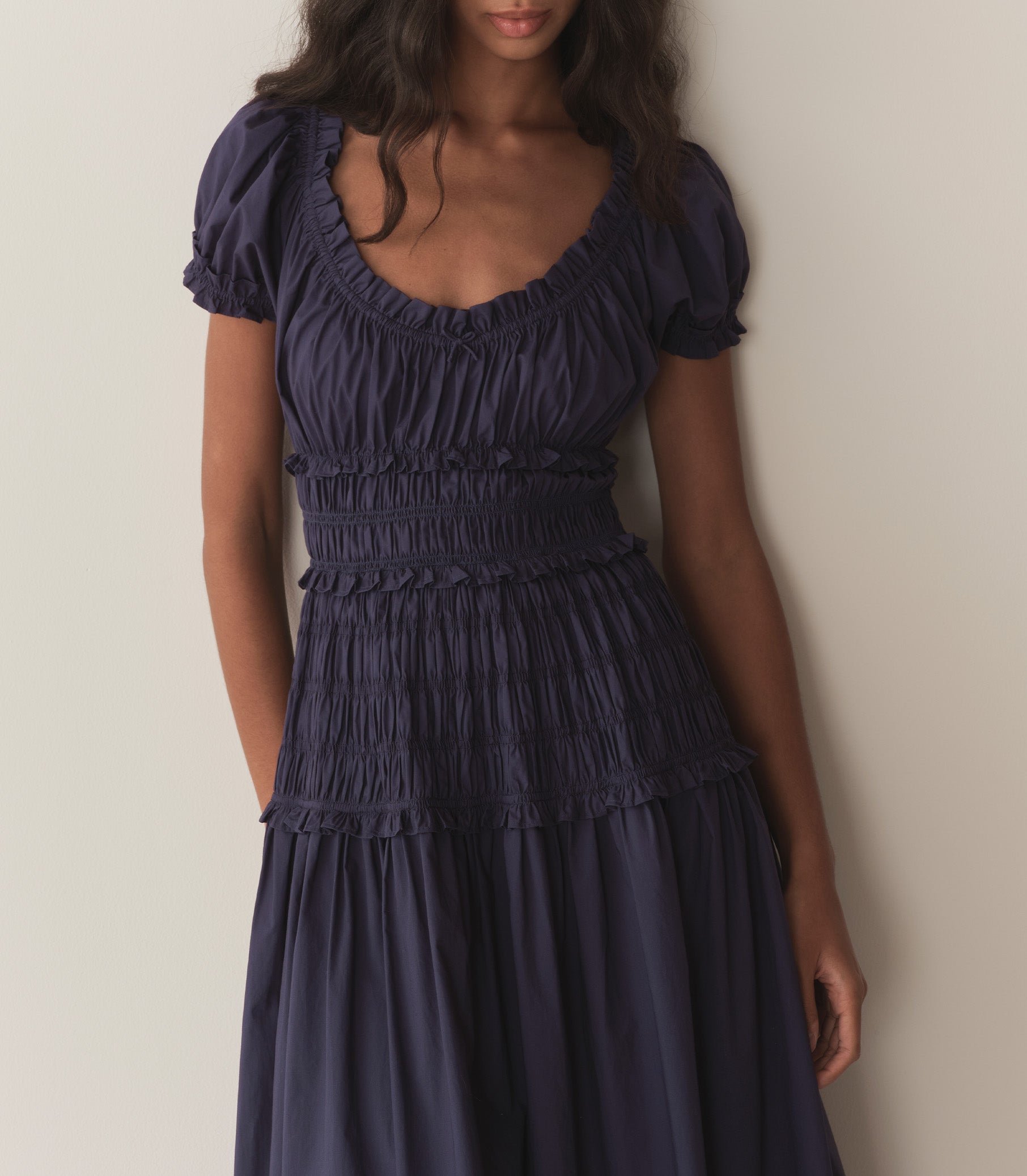 Rocio wears a dark blue dress with puffed sleeve and ruching along the bodice. 3