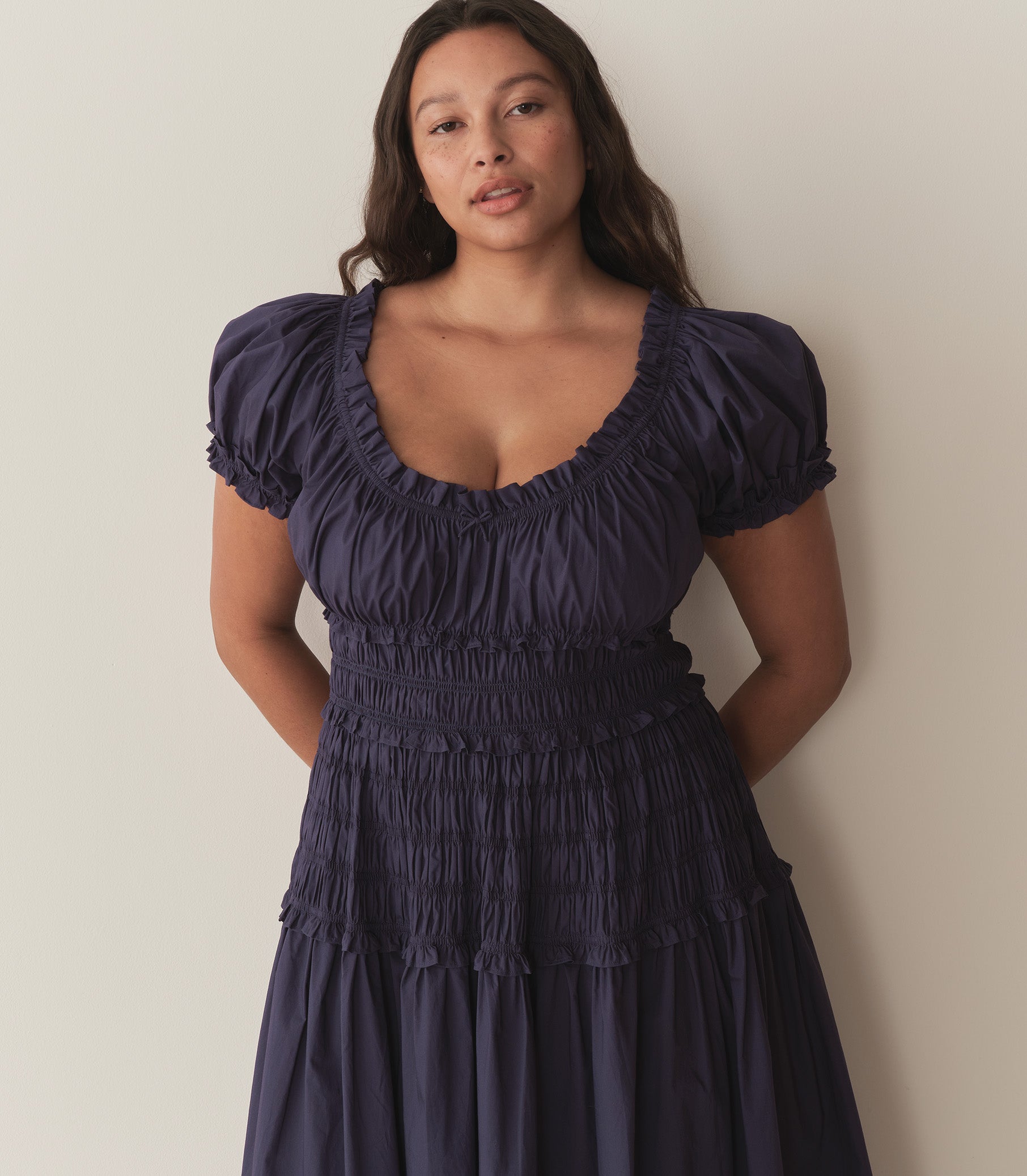 Alana wears a dark blue dress with puffed sleeve and ruching along the bodice. 2
