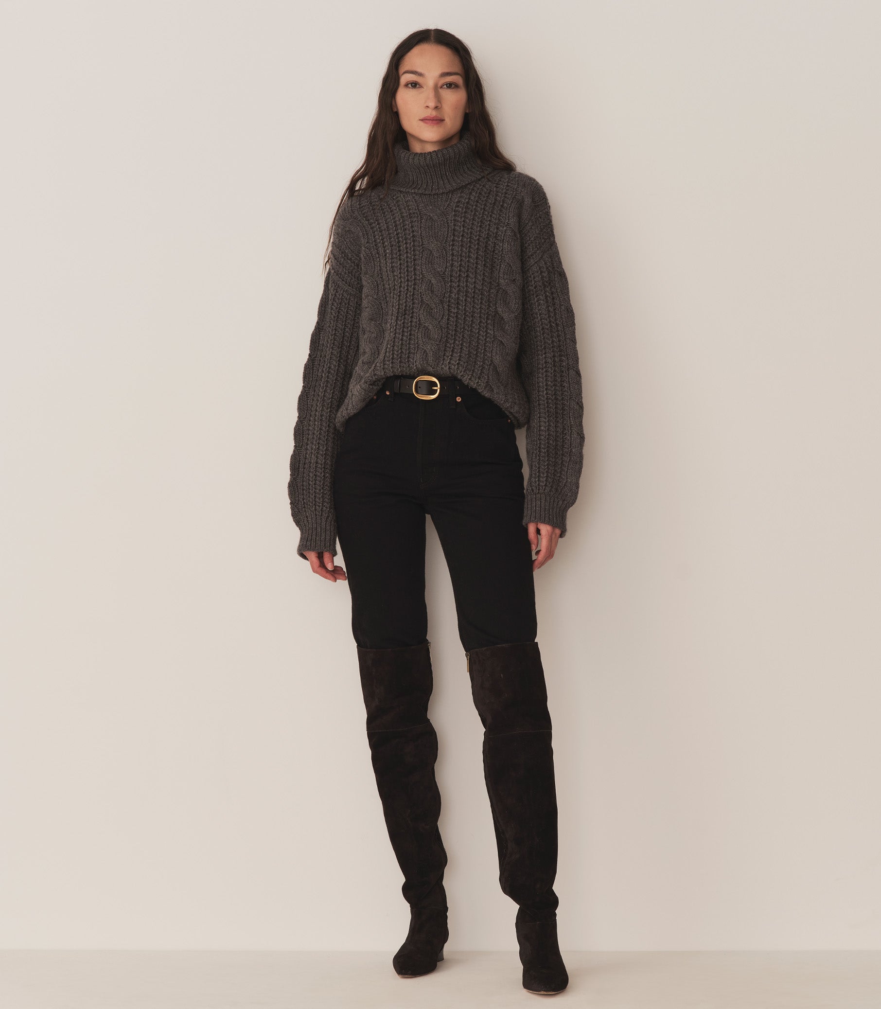 Person wearing a dark grey turtleneck sweater, black jeans, and black suede knee-length boots. 3