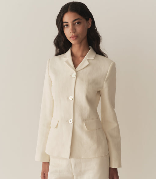 Rocio is wearing an off white blazer paired with its matching pants, a bandana, and brown kitten mules.