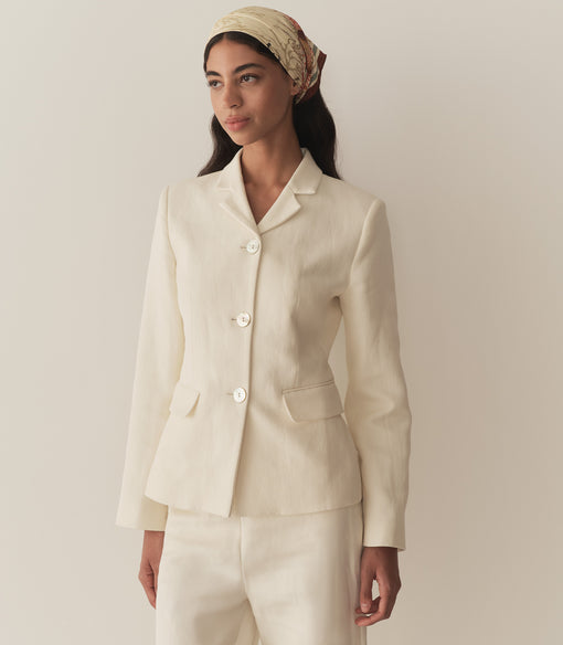 Rocio is wearing an off white blazer paired with its matching pants, a bandana, and brown kitten mules.
