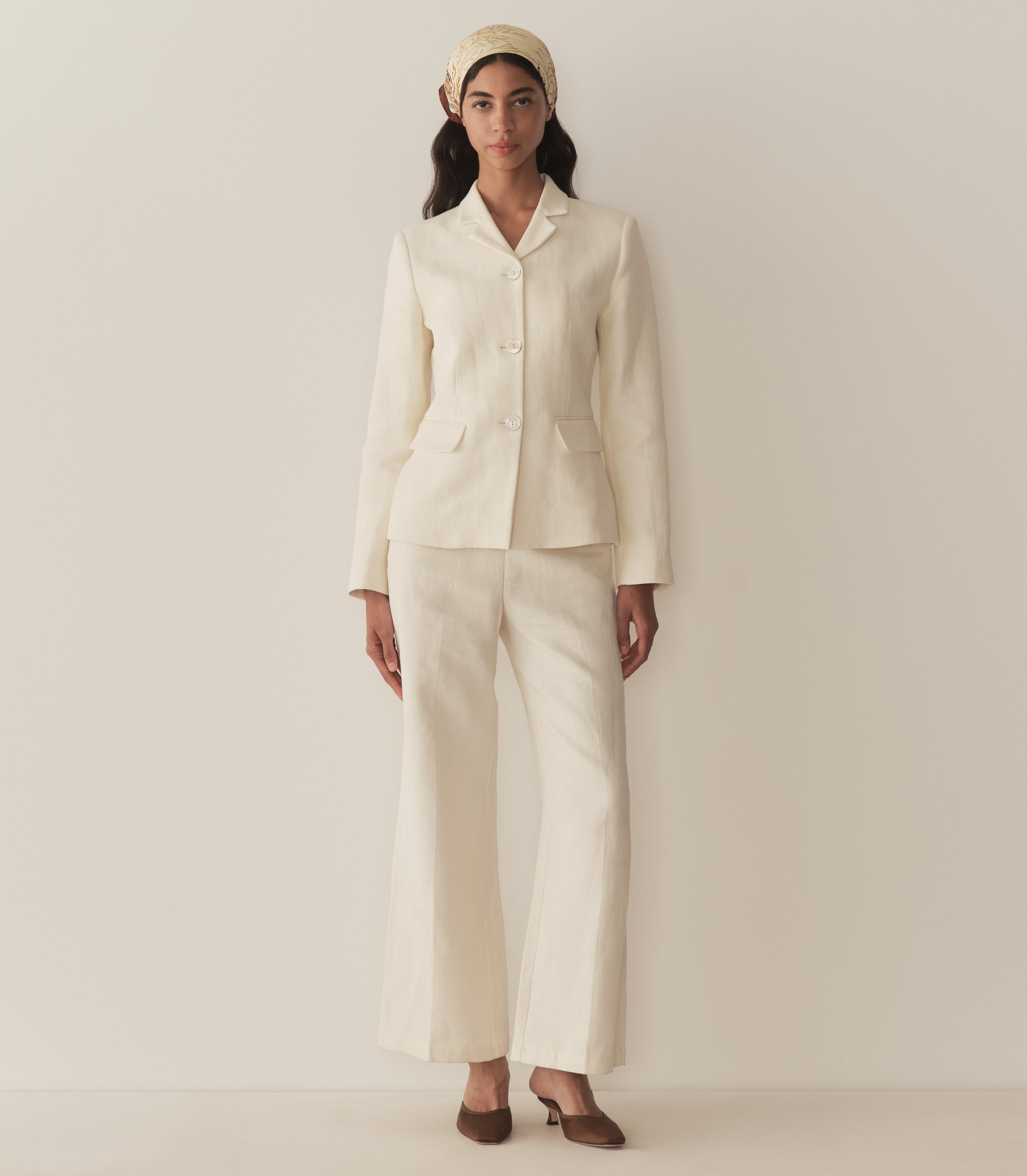 Rocio is wearing an off white blazer paired with its matching pants, a bandana, and brown kitten mules. 2