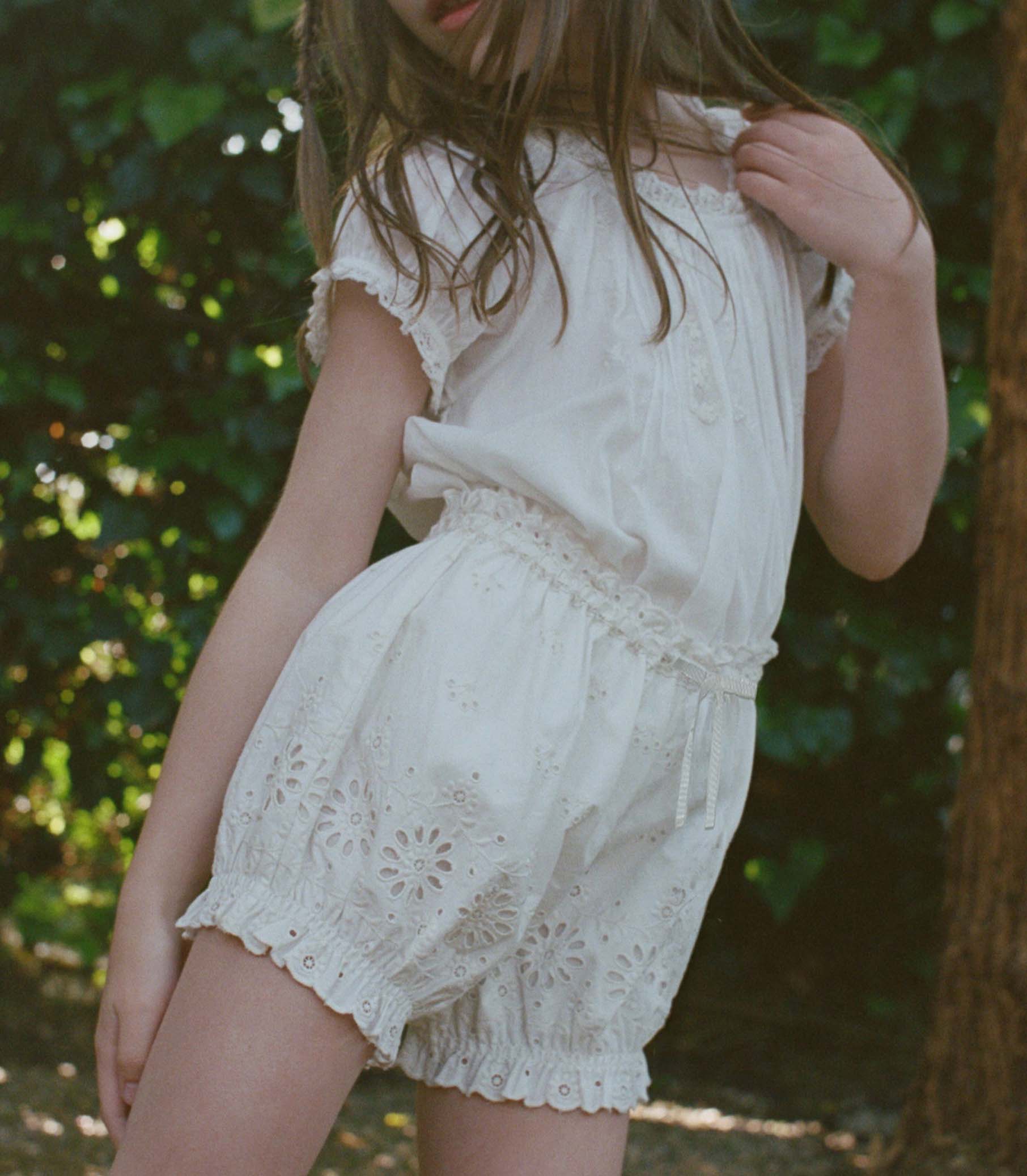 Kid wearing white lace shorts in a natural setting