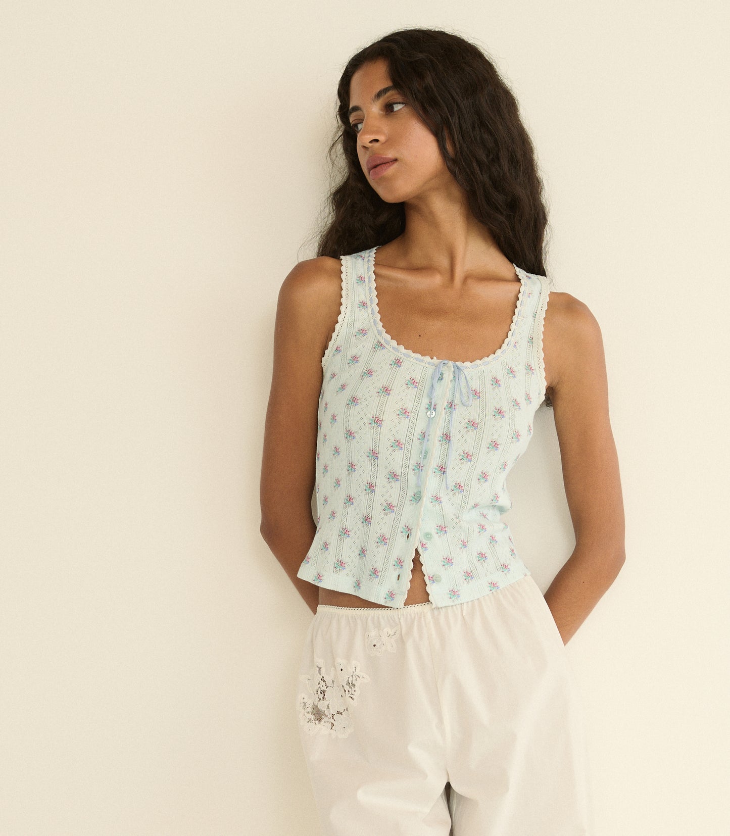 Woman wearing a light blue floral sleeveless top against a beige background
