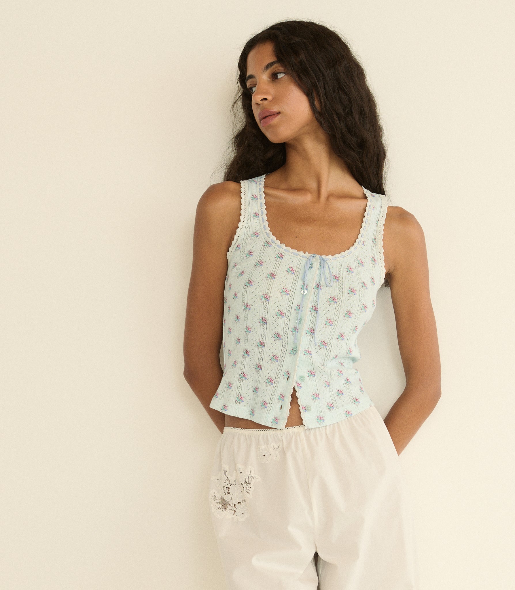 Woman wearing a light blue floral sleeveless top against a beige background