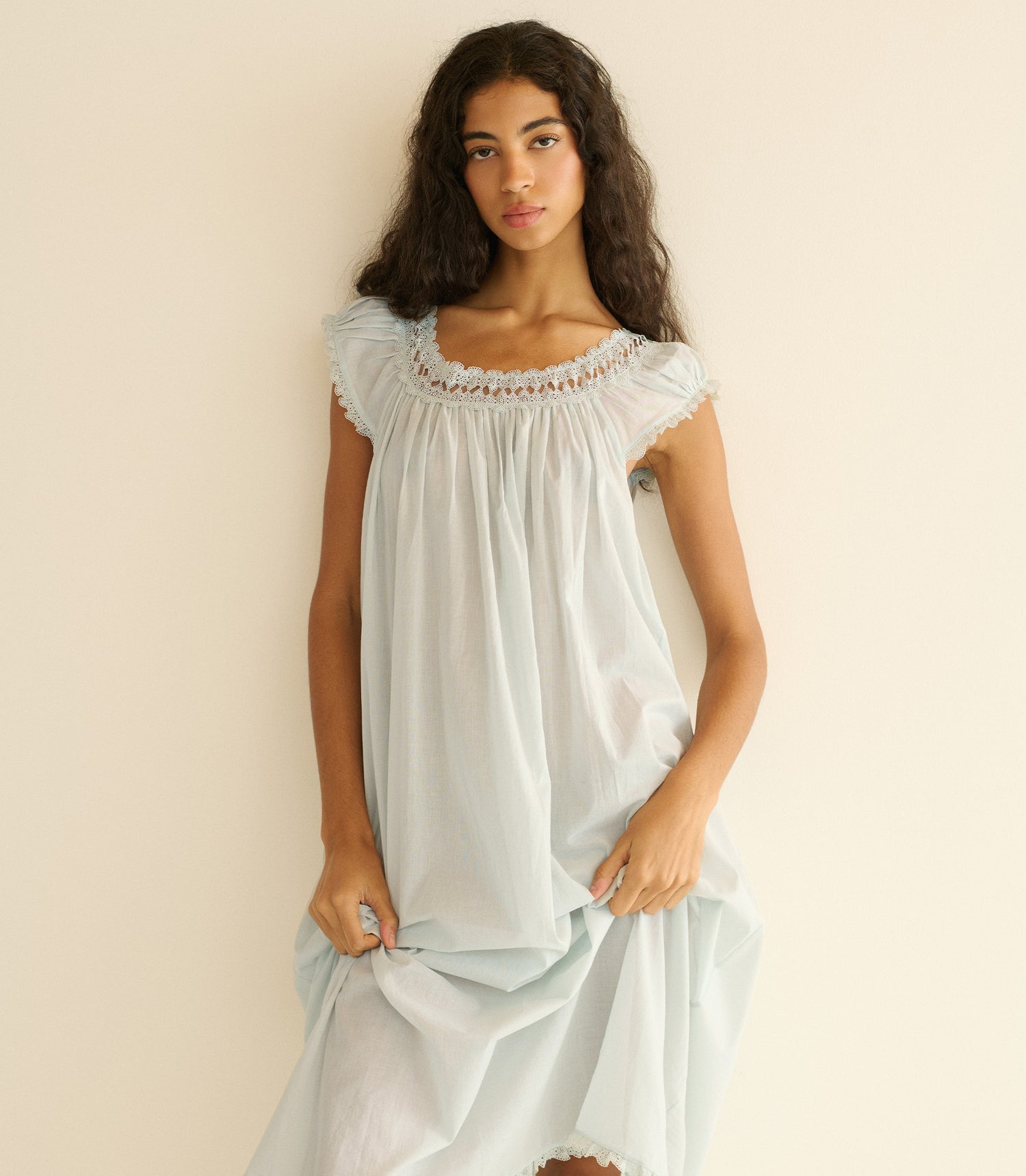 Woman wearing a light blue nightgown against a beige background