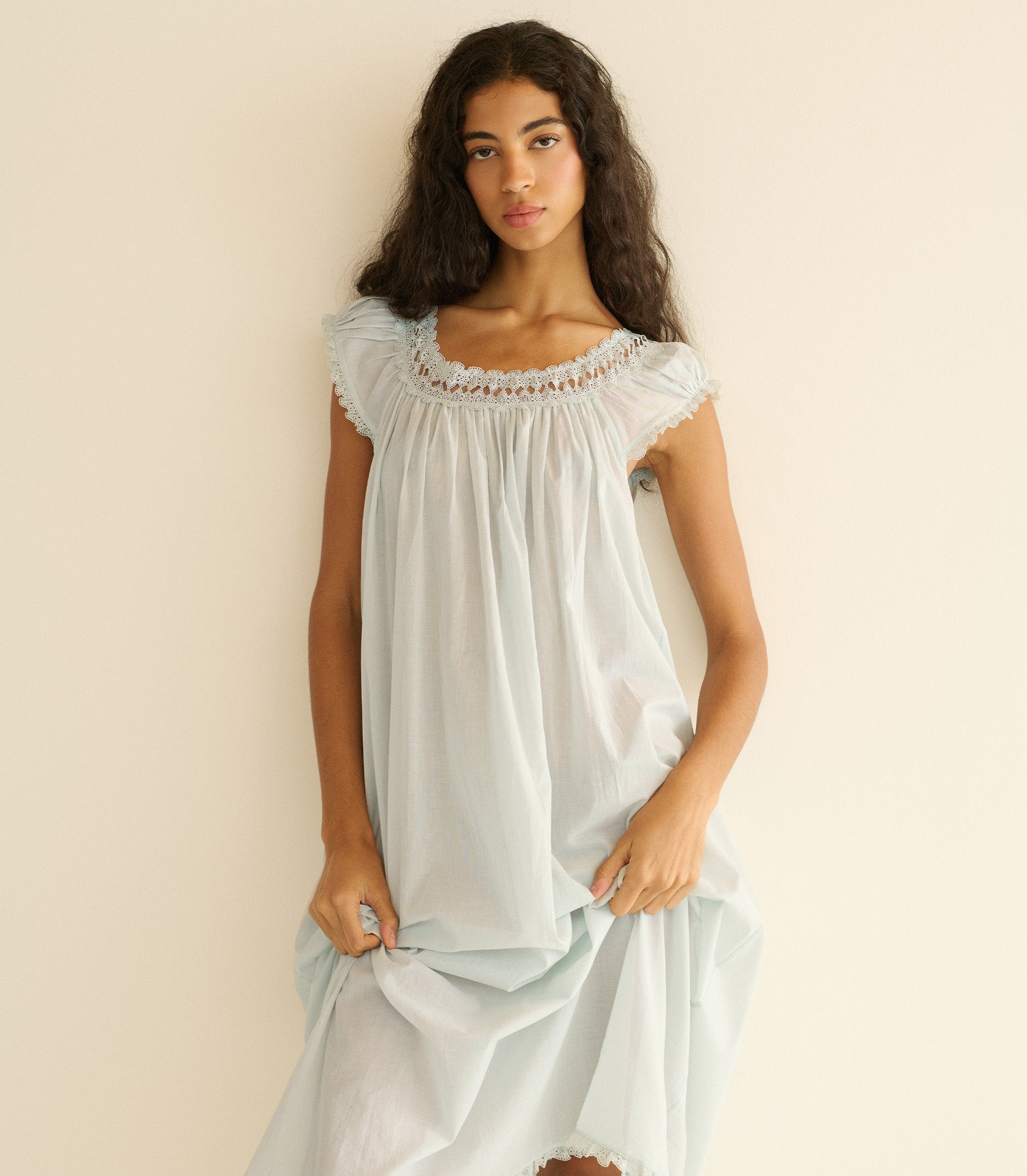Woman wearing a light blue nightgown against a beige background 1