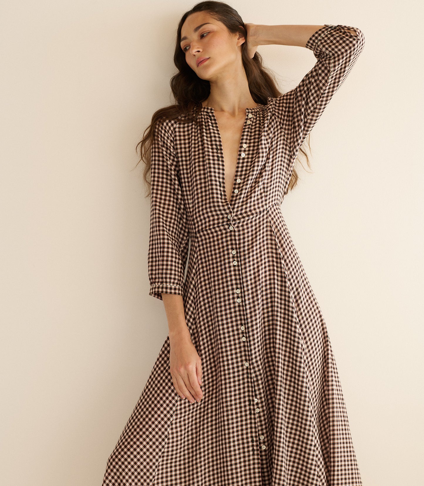 Woman wearing a black and white checkered dress against a beige background
