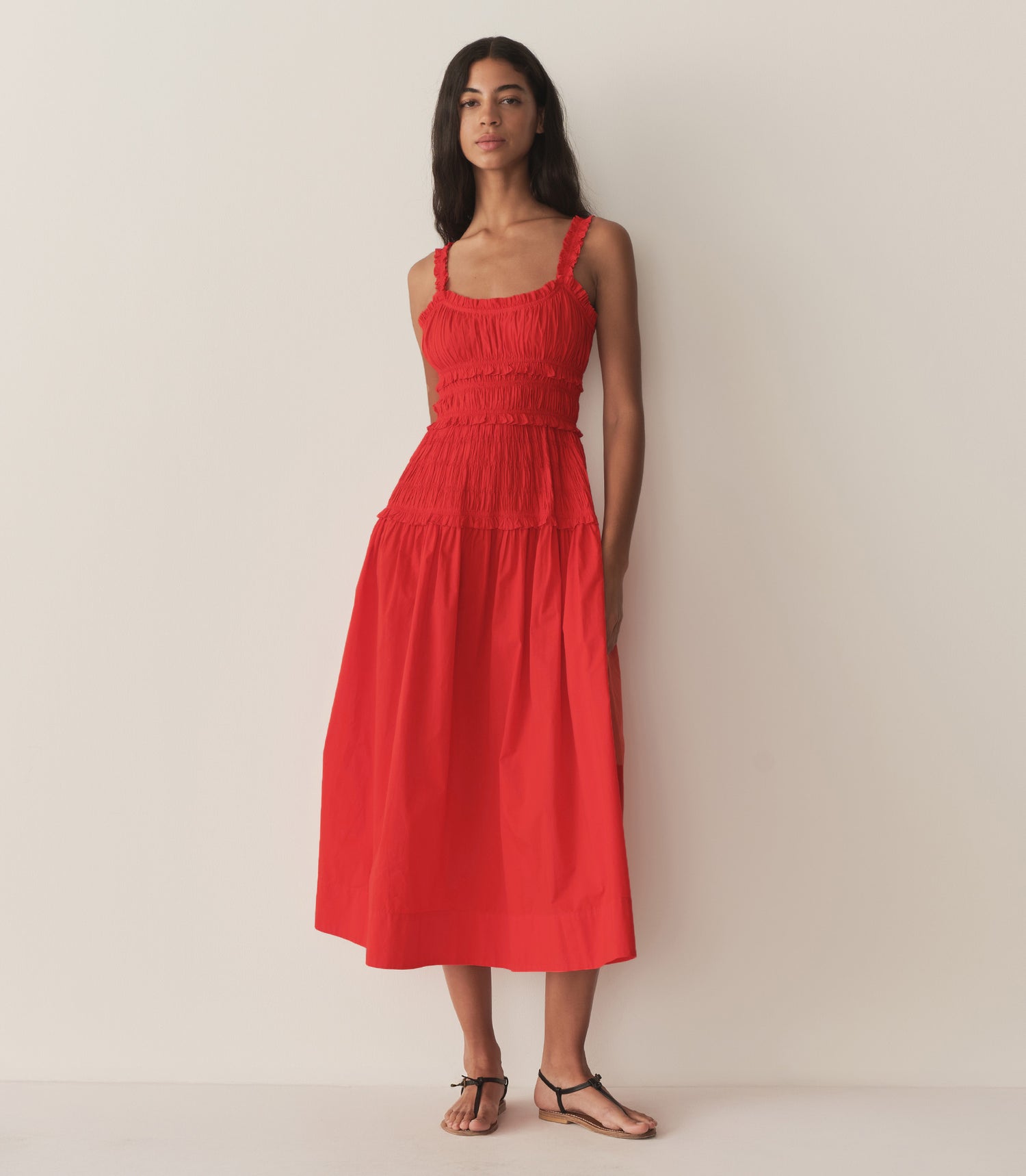 Rocio is wearing a red mid-length dress with sandals.