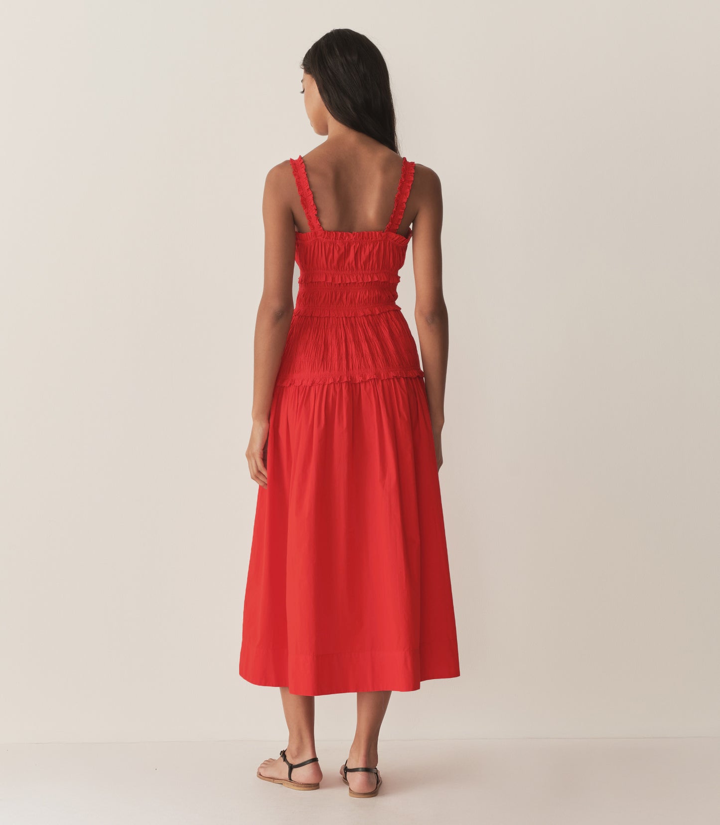 Rocio is wearing a red mid-length dress with sandals.