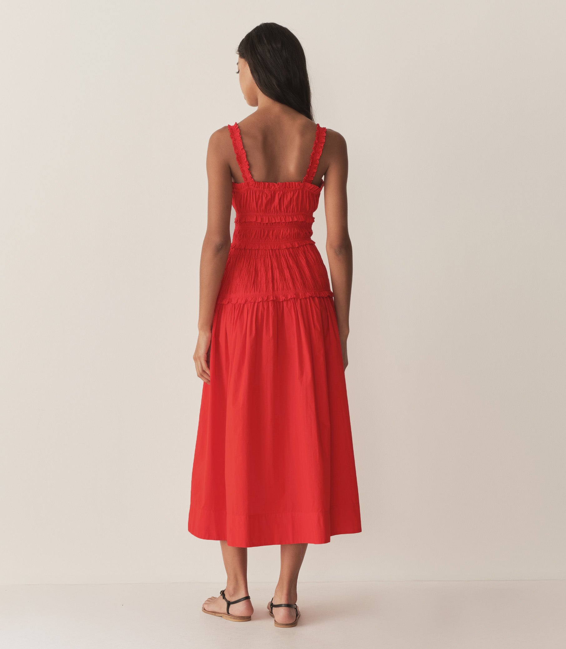 Rocio is wearing a red mid-length dress with sandals. 4