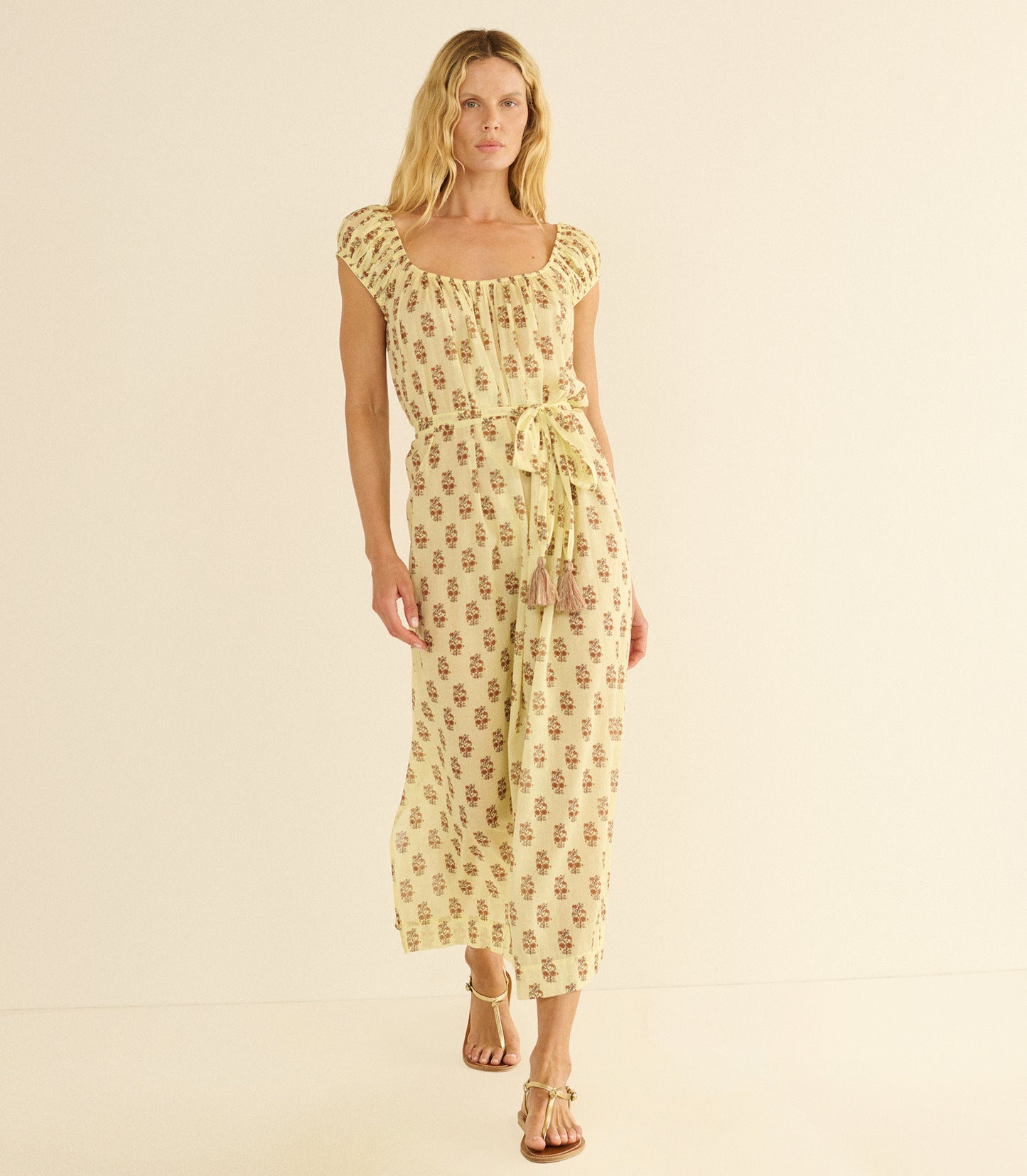 Woman wearing a yellow floral dress on a beige background