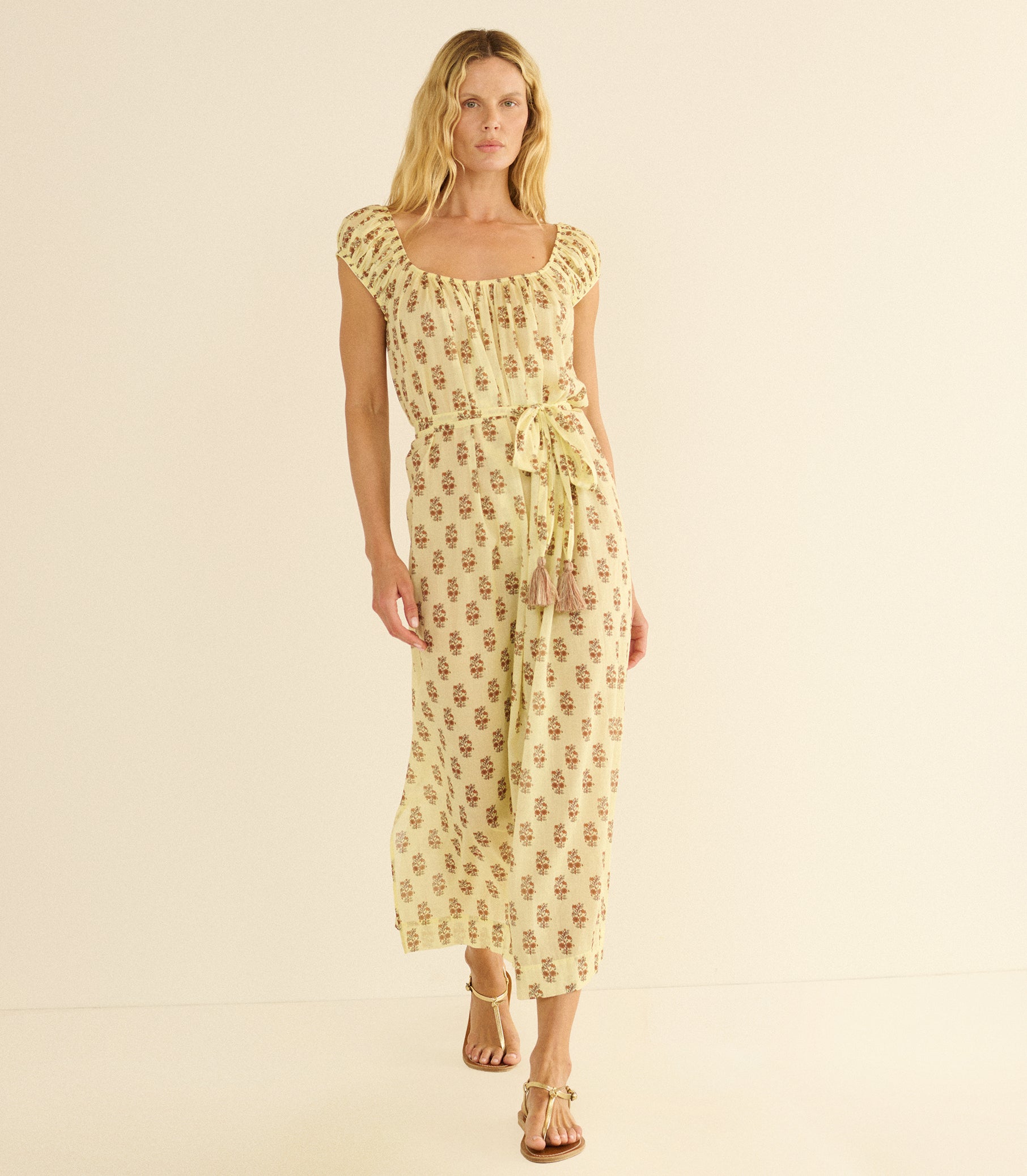 Woman wearing a yellow floral dress on a beige background