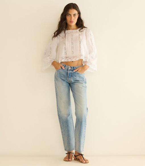 Woman wearing a white blouse and light blue jeans on a beige background