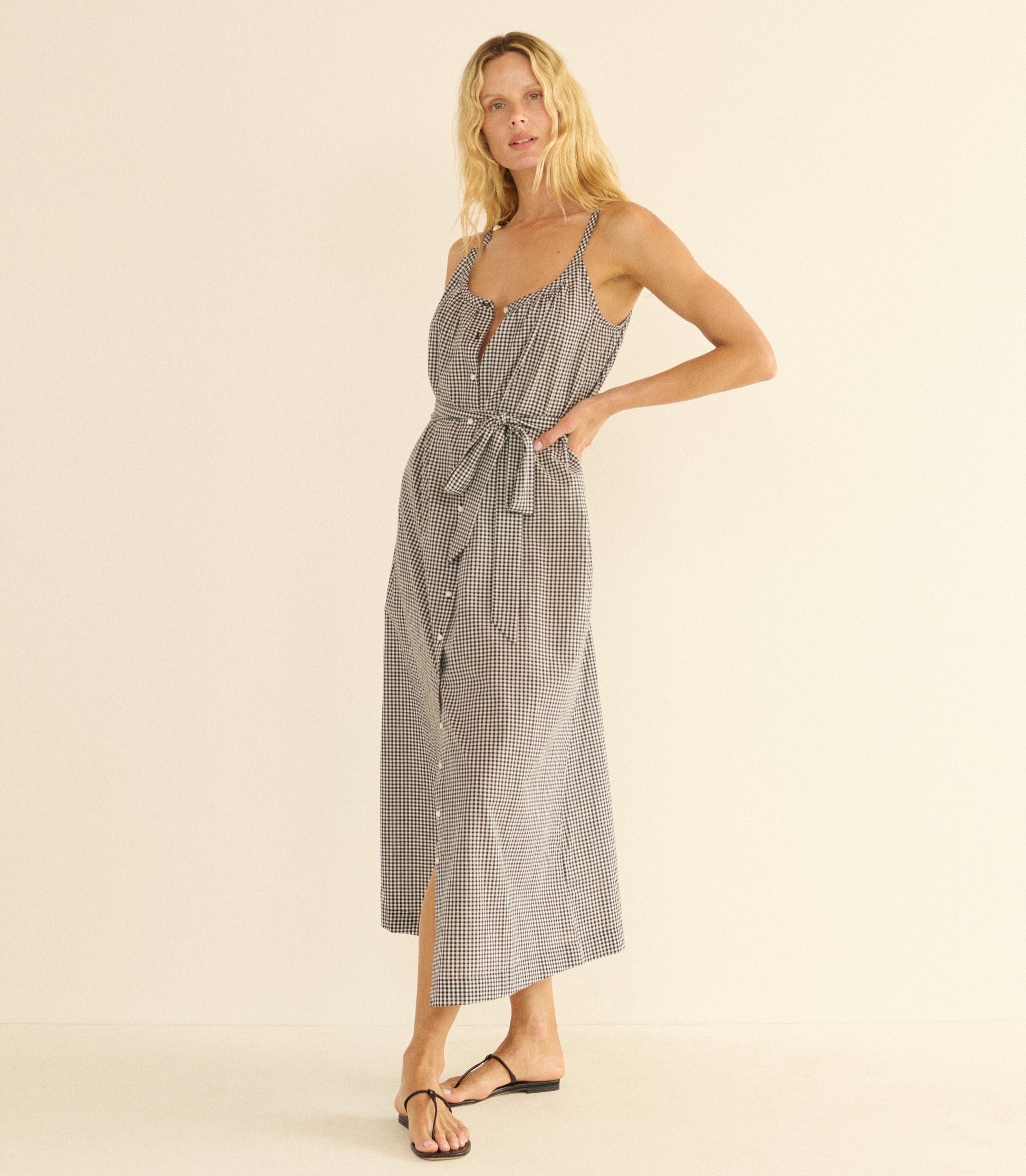 Woman wearing a black and white maxi dress and black sandals against a beige background 1
