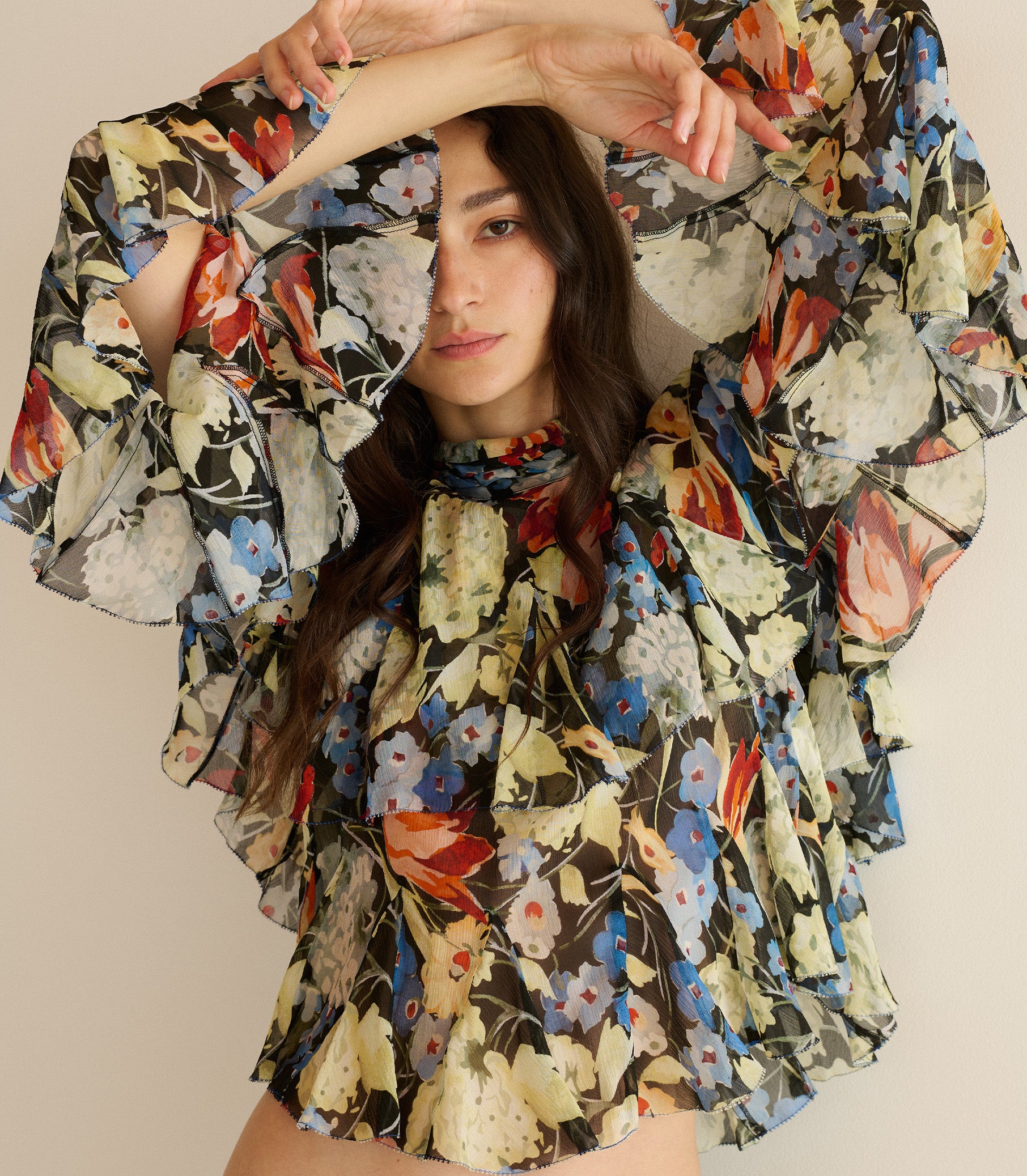 Woman wearing a colorful floral dress against a plain background