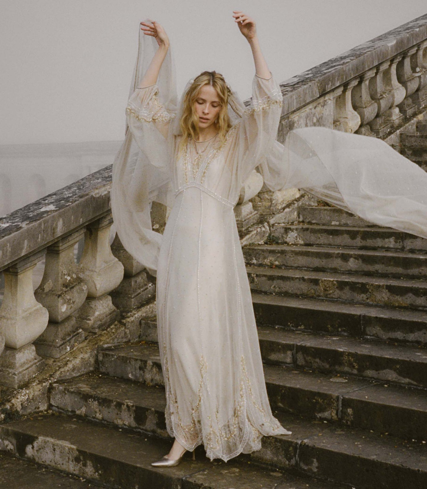 Woman in a flowing white dress standing on stone steps