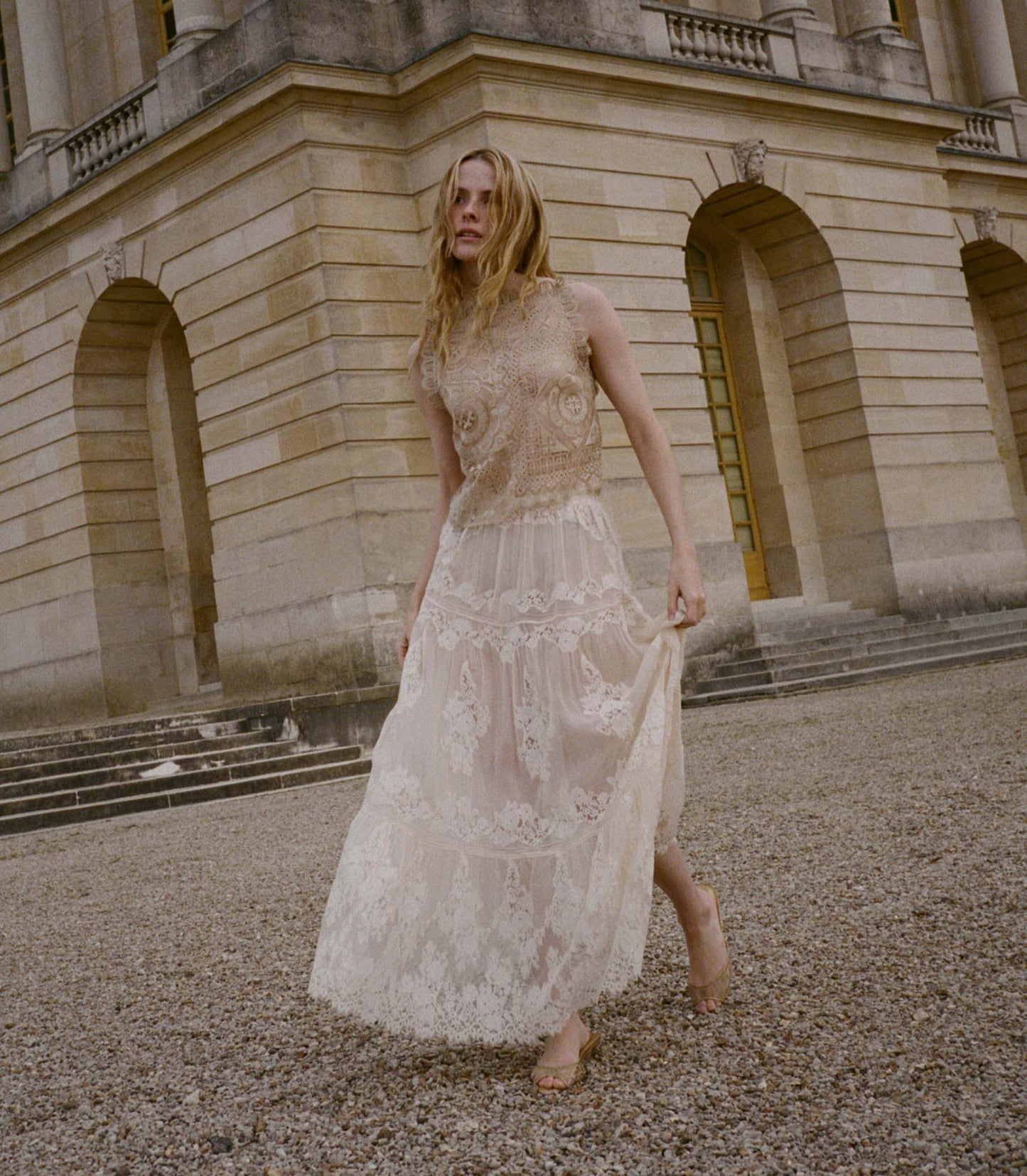 Woman in a white lace skirt standing in front of a classical building.