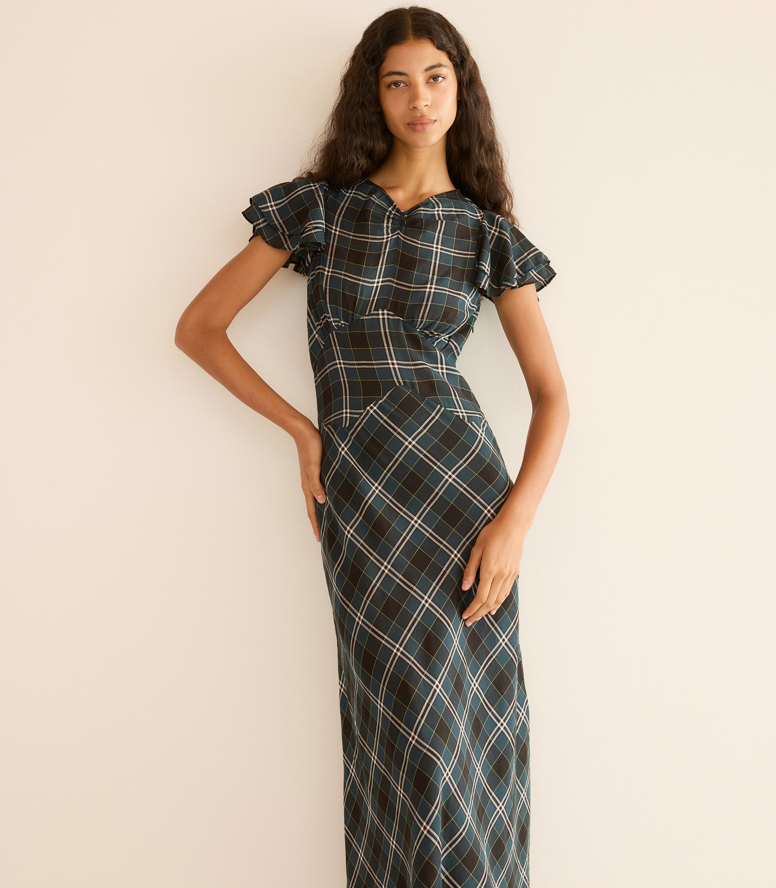 Woman wearing a plaid dress against a plain background