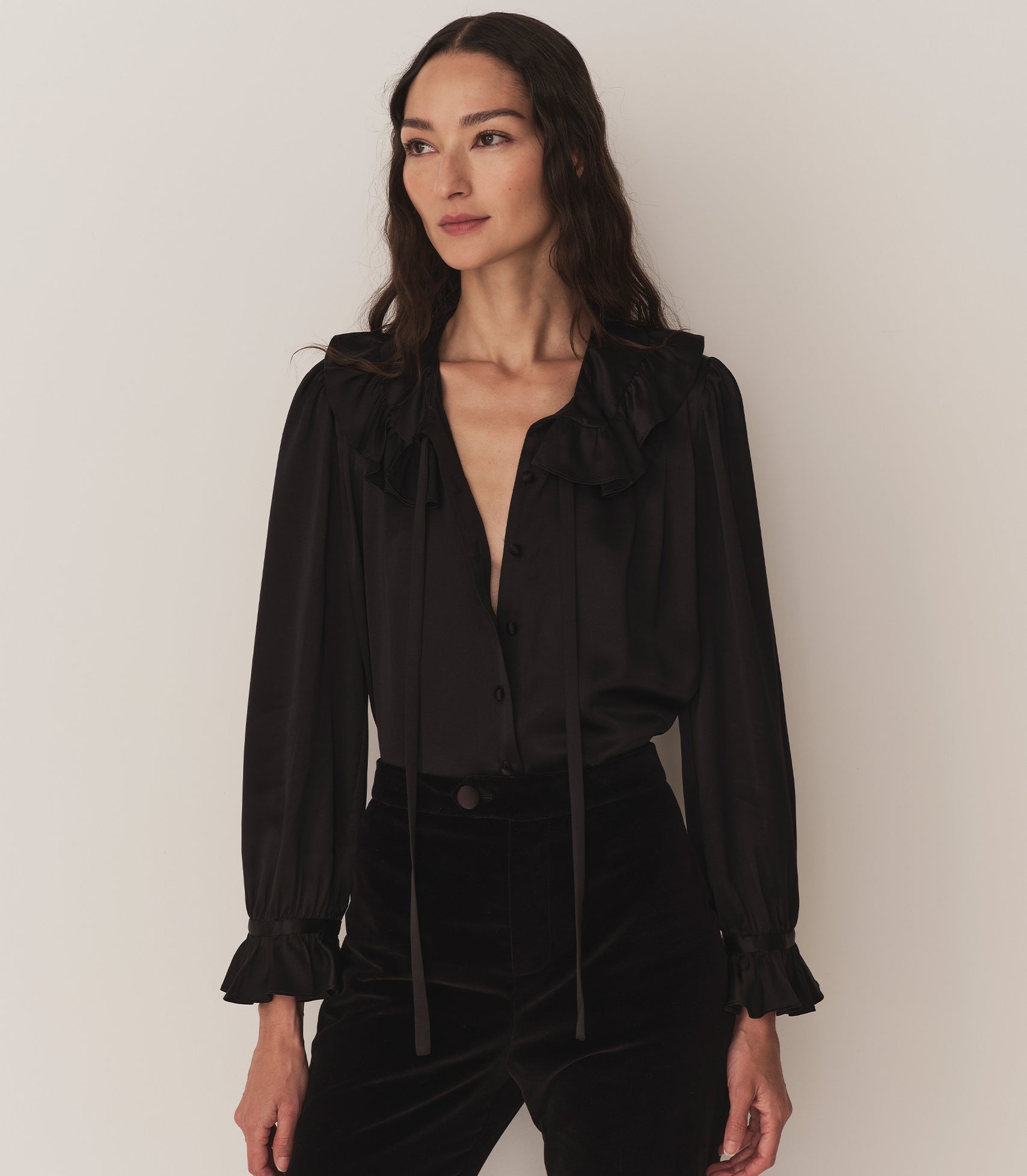 Person wearing a silk black top and black velvet pants.