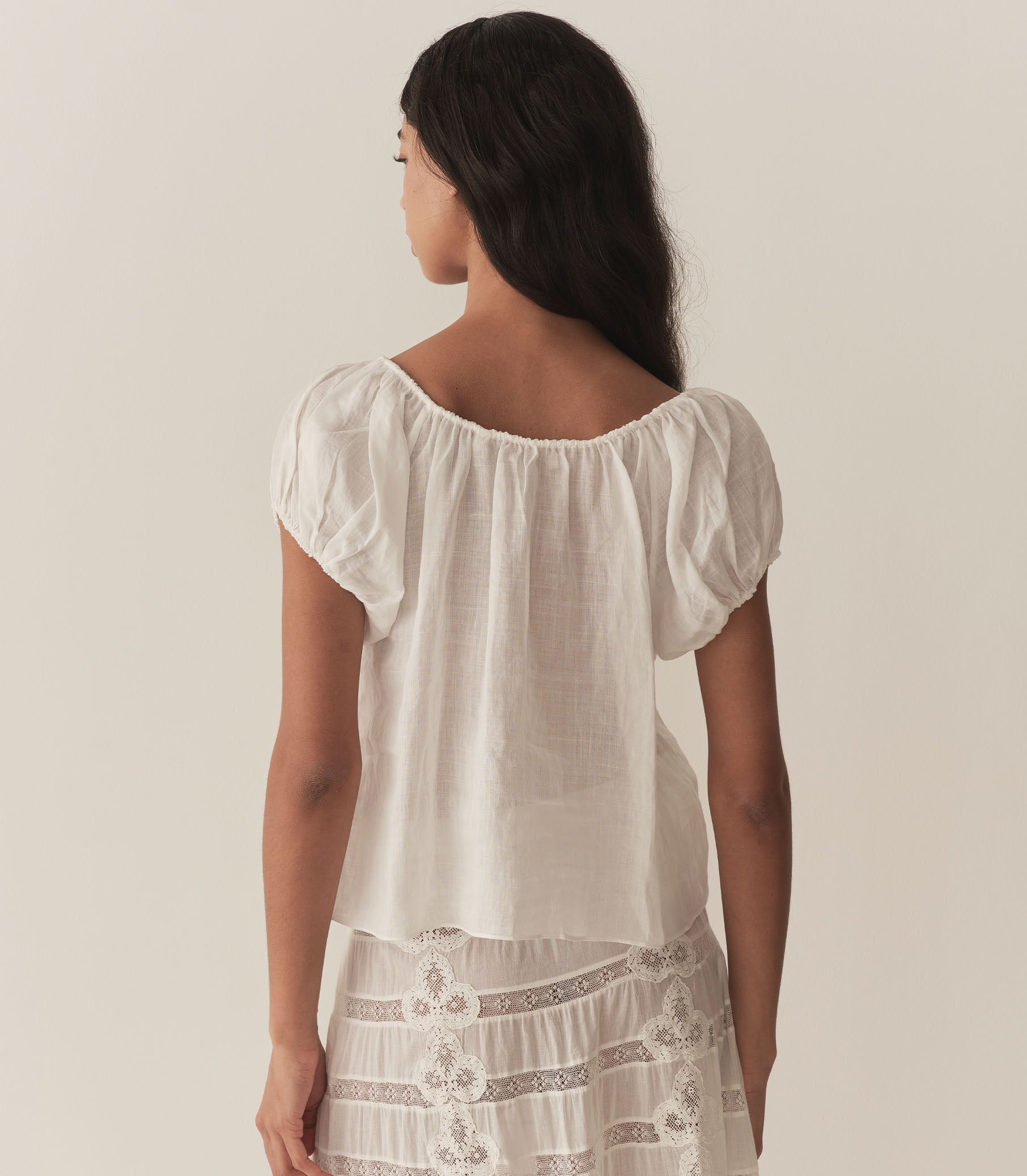 Rocio is wearing a white short puff sleeve blouse paired with a white maxi skirt. 4