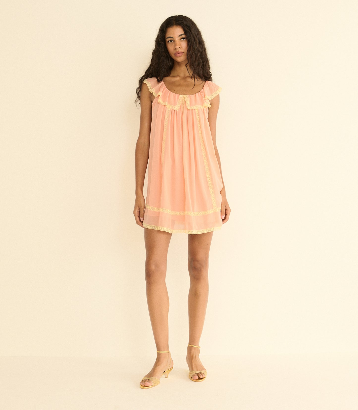 Woman wearing a peach dress against a beige background