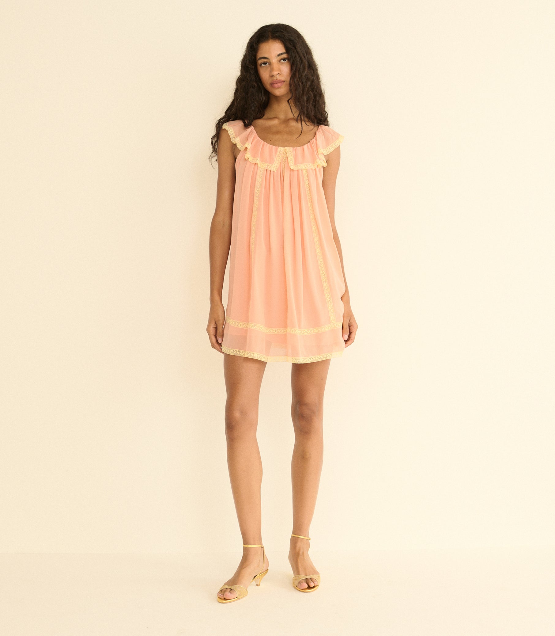 Woman wearing a peach dress against a beige background 1
