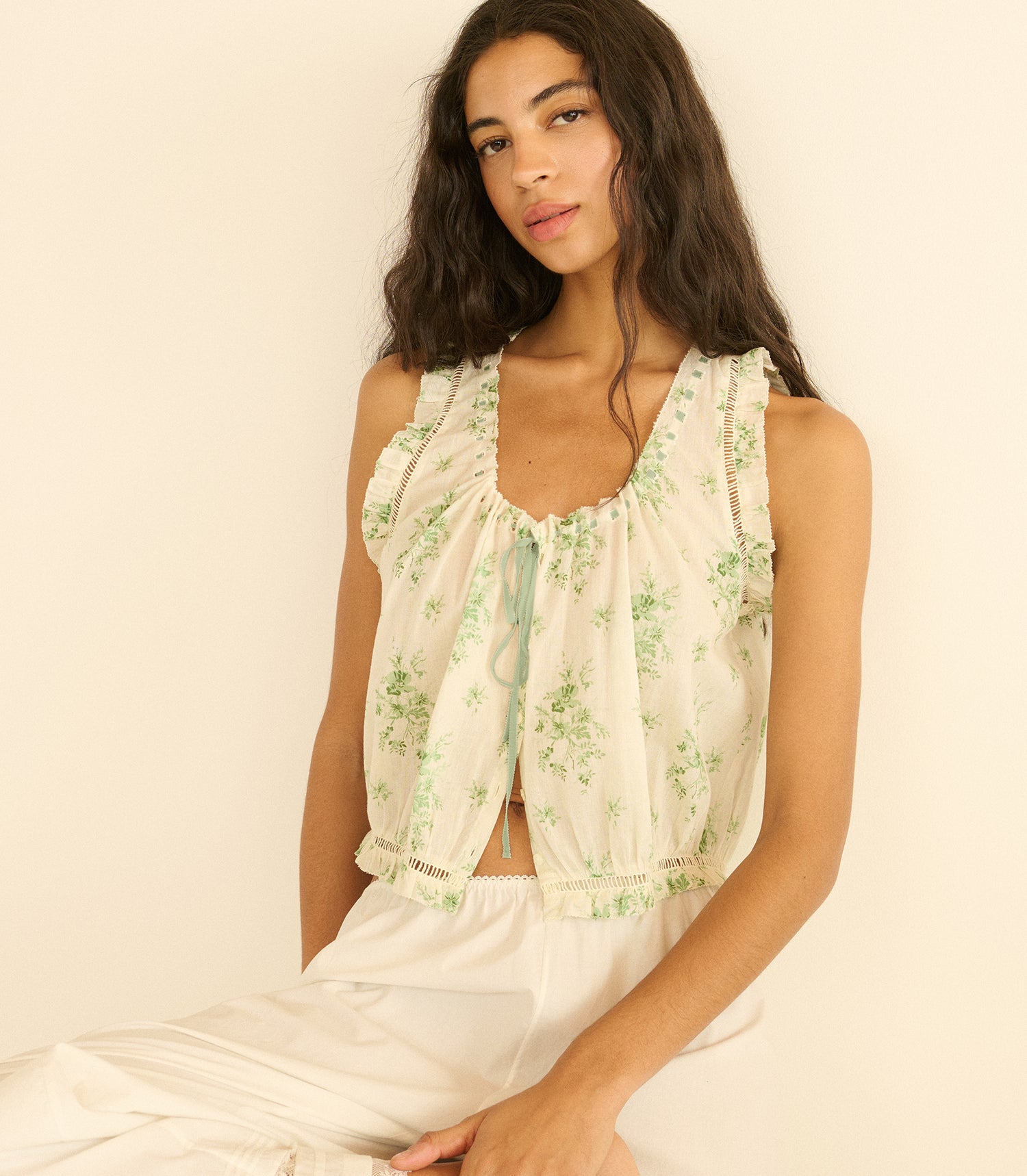 Woman wearing a floral sleeveless top against a plain background