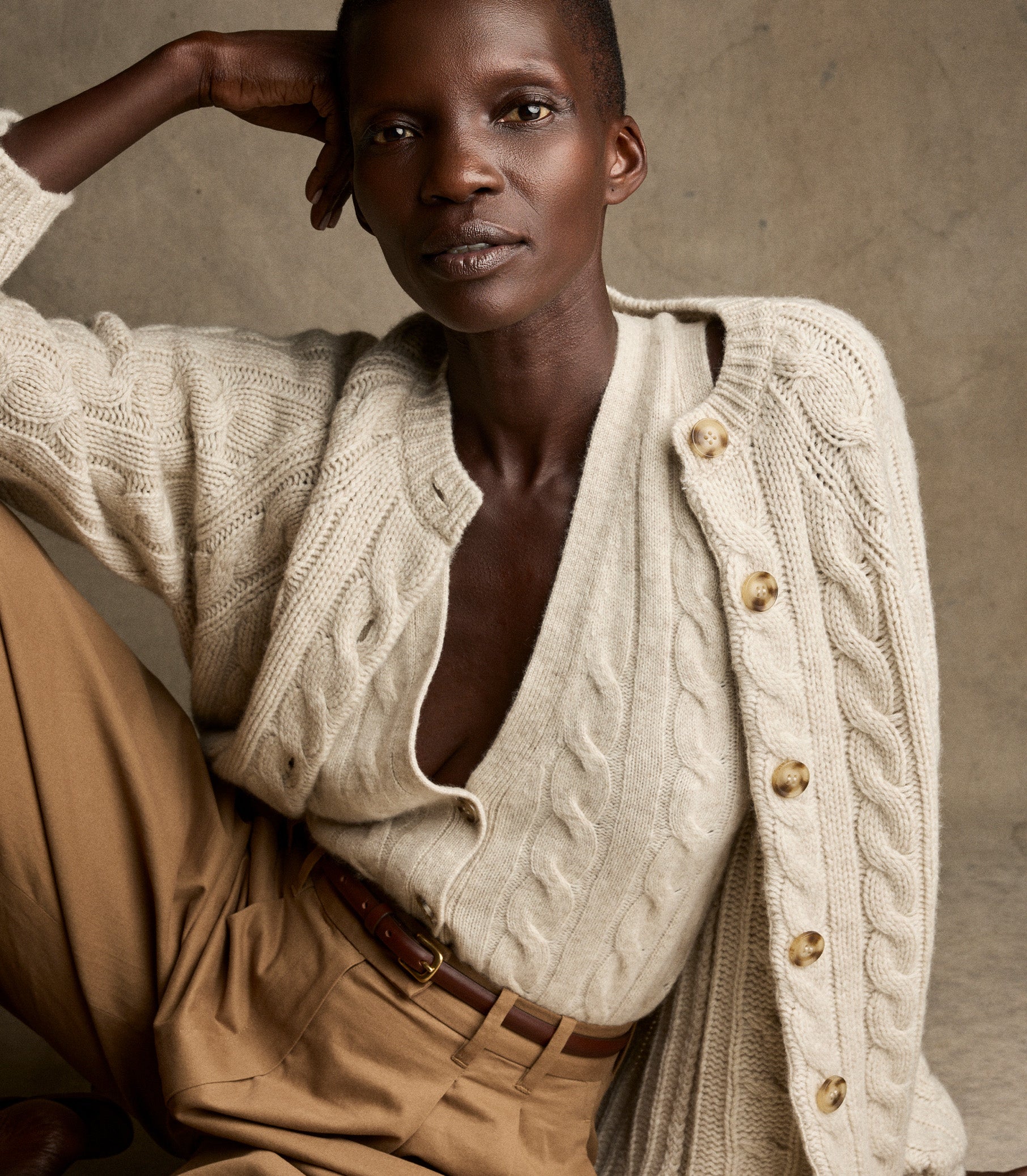Person wearing a cream-colored cable knit cardigan against a neutral background