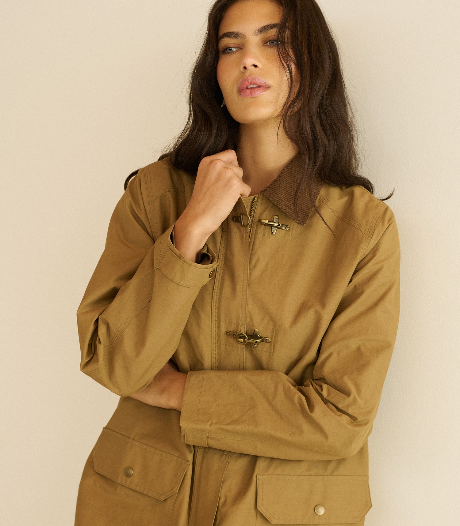 Woman wearing a brown jacket against a beige background
