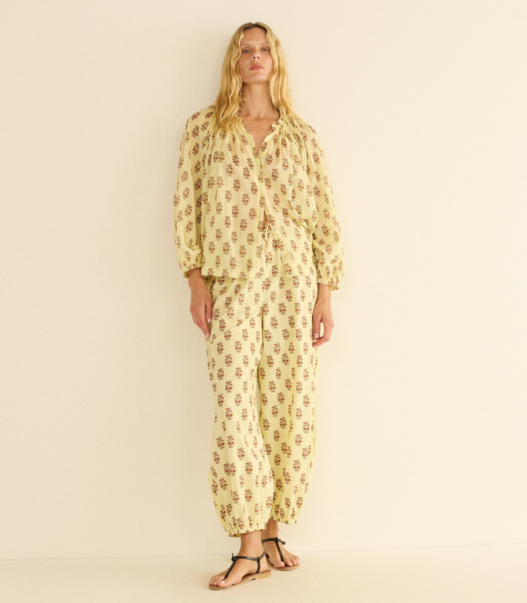 Woman wearing a yellow patterned outfit on a beige background 1
