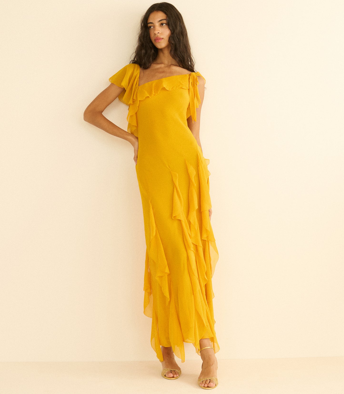 Woman wearing a yellow off-shoulder dress on a beige background