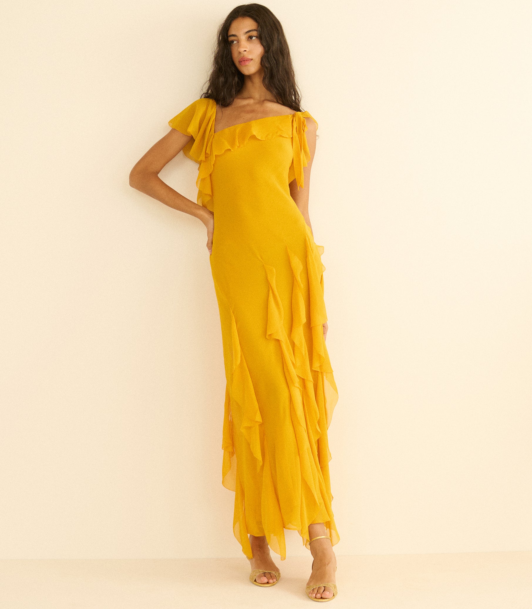 Woman wearing a yellow off-shoulder dress on a beige background